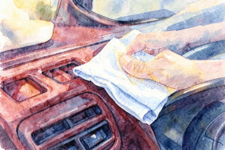 Close-up de um painel de carro sendo limpo com um pano de microfibra, mostrando detalhes do acabamento.